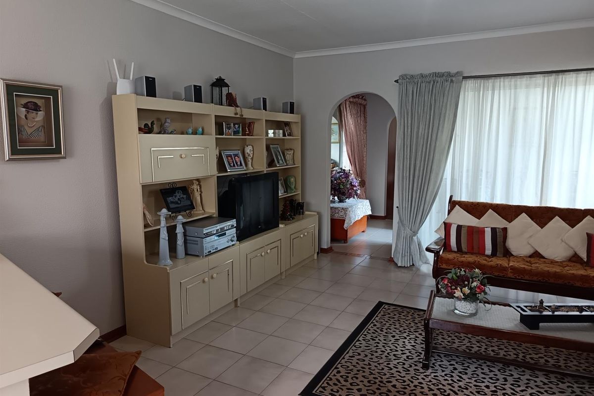 A living room featuring tiled flooring, a built-in shelving unit, and an arched doorway leading to an adjacent space.