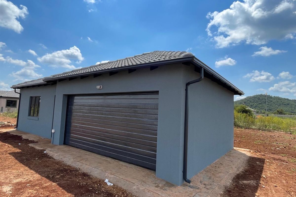 A modern, newly constructed detached garage featuring a dark grey finish, tiled roof, and a sectional garage door.