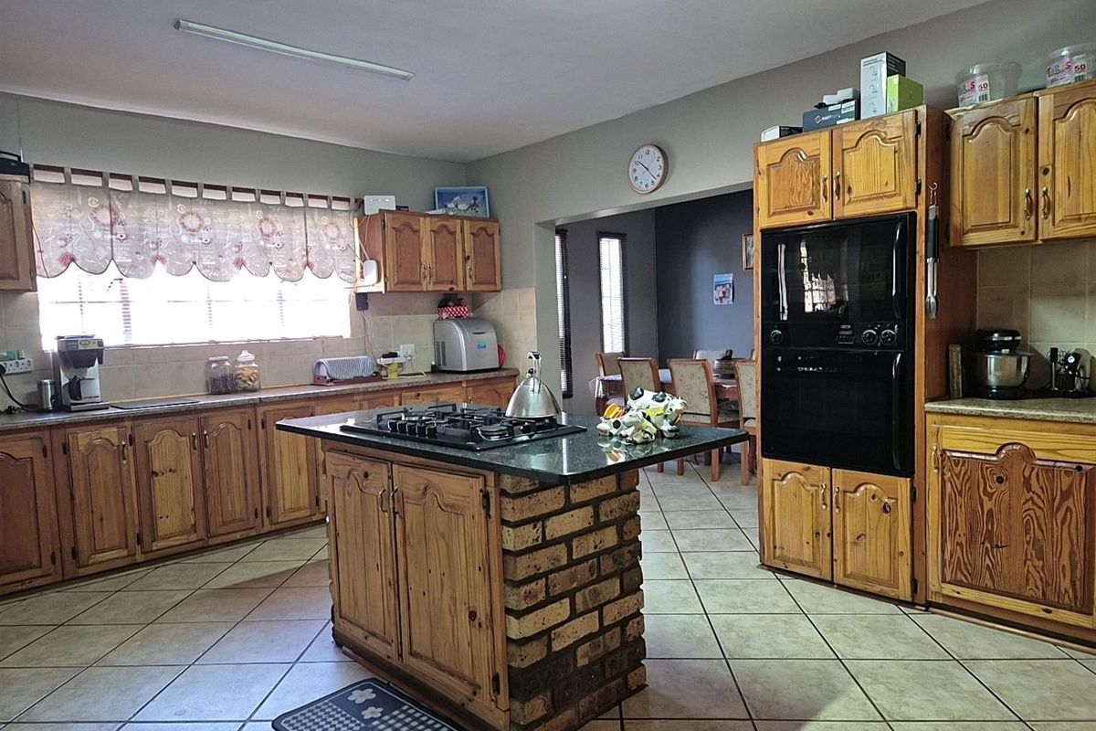 Spacious kitchen featuring a central brick-base island with a built-in gas hob, ample wooden cabinetry, and integrated wall oven.