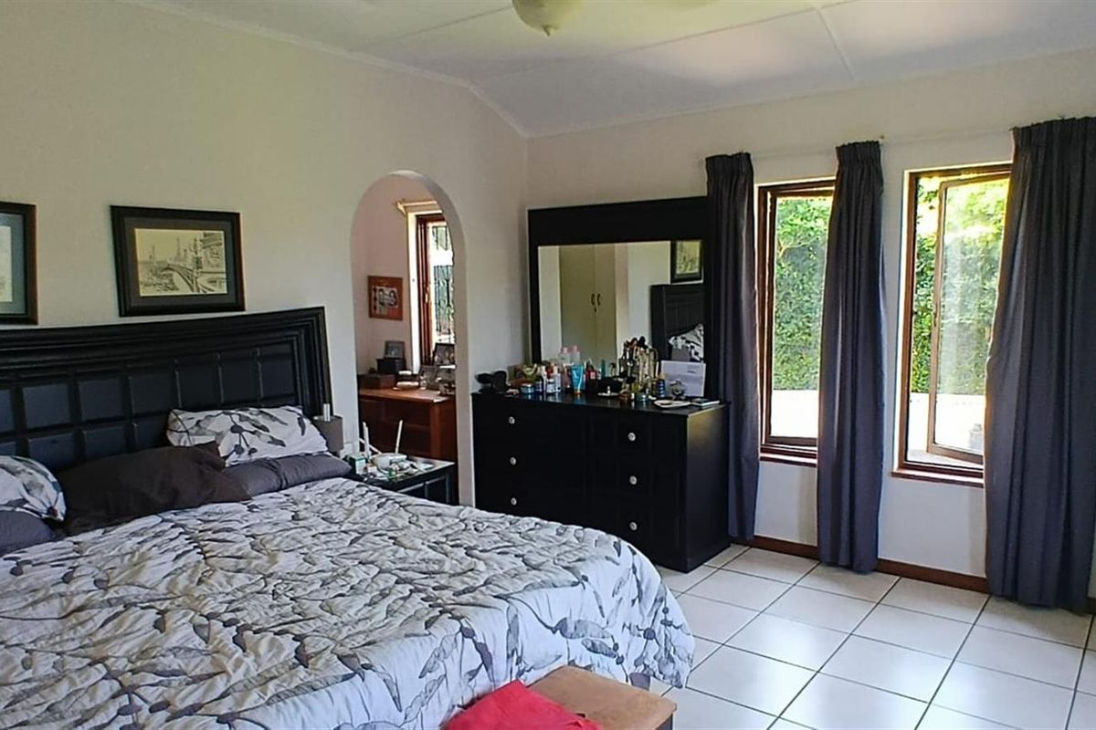 Spacious bedroom featuring tiled flooring, large windows allowing natural light, and an arched doorway leading to an adjoining space.