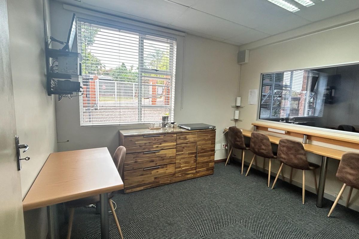 A functional office space featuring a built-in desk, carpeted flooring, and a large window providing natural light.