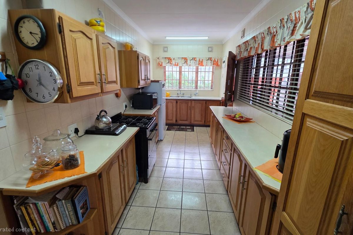 A functional galley-style kitchen featuring traditional timber cabinetry, tiled flooring, and ample counter space with a built-in stove and double sink.