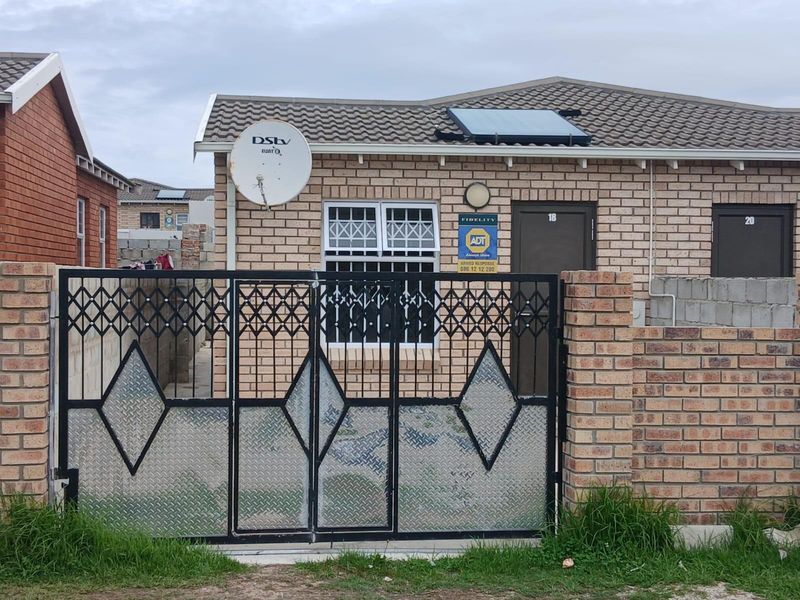 Front elevation of a face brick house featuring a tiled roof, solar water heating system, and secure gated entrance.