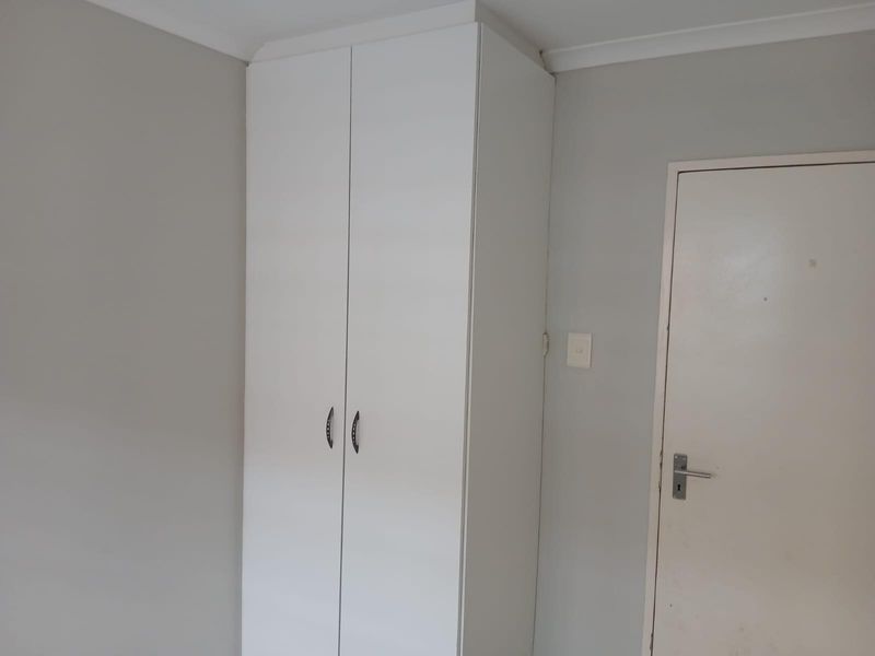 A clean, neutral bedroom featuring a white built-in wardrobe and standard internal door, providing a blank canvas for personalization.