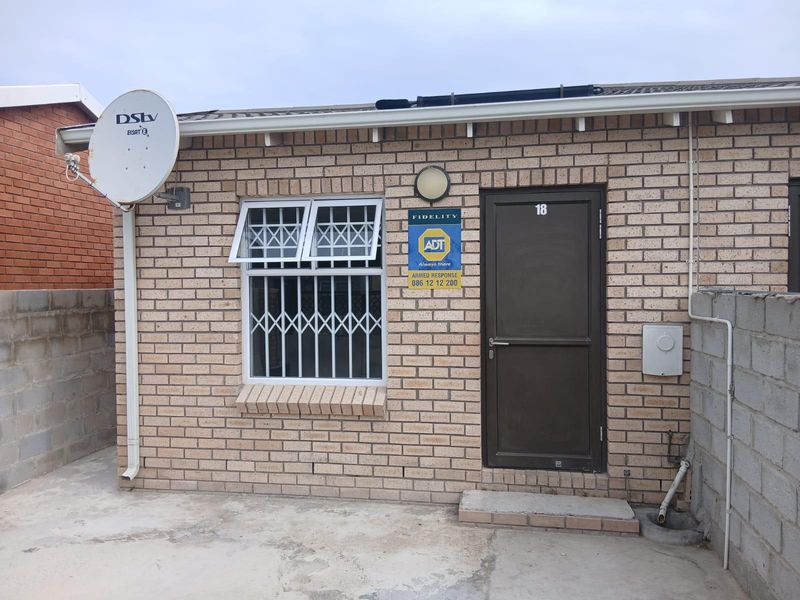 Front exterior view of a face brick house featuring a security door, window security bars, satellite dish, and solar water heating system.