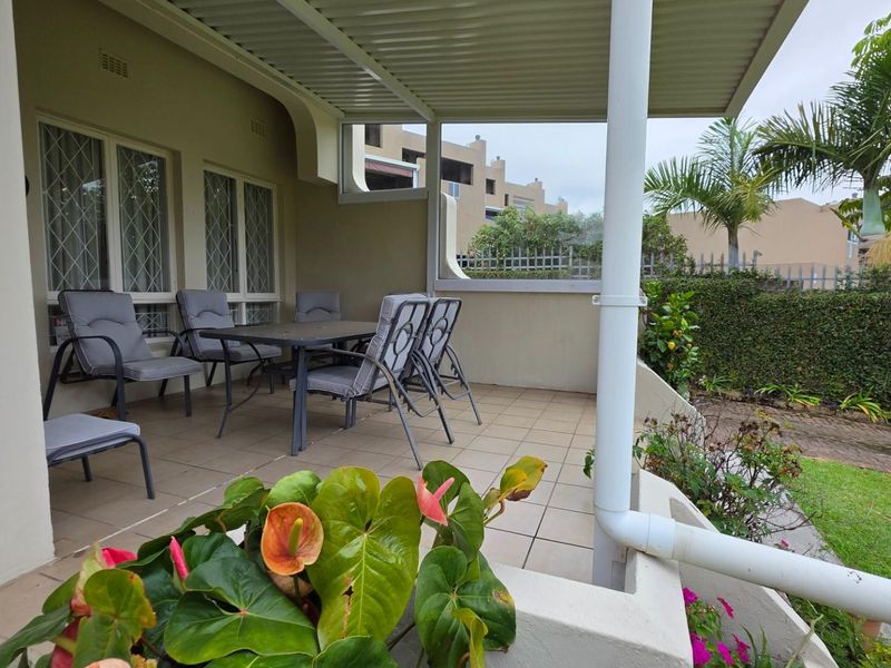 A covered patio area featuring tiled flooring, providing a seamless transition to the private garden space.