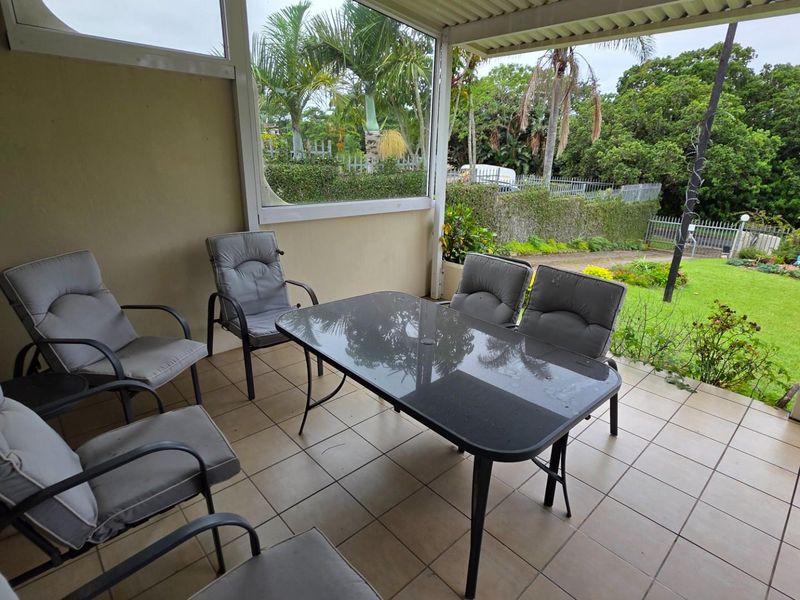 A covered patio area featuring tiled flooring and a view overlooking the private garden.