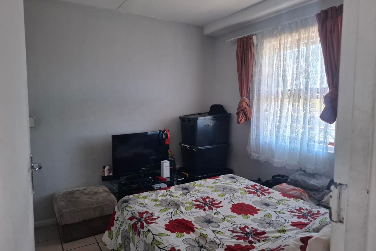 A bedroom featuring tiled flooring and a window with curtain fixtures, providing a functional living space.