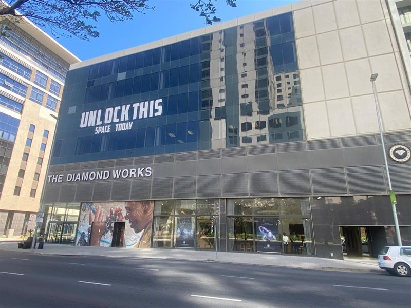 Commercial building facade featuring large glass curtain walls, modern metal cladding, and prominent street-level signage for The Diamond Works.
