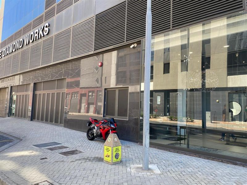 Modern commercial building facade featuring large glass display windows, polished stone cladding, and integrated metal louvers at street level.