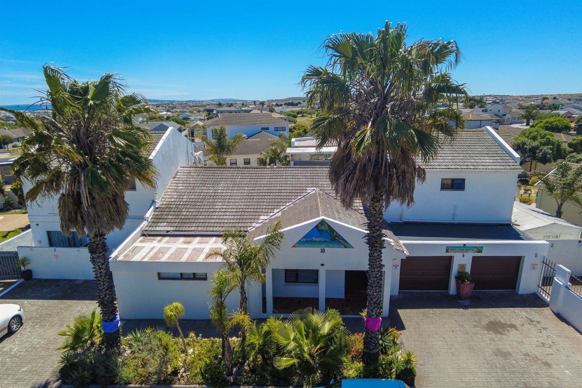 Aerial view of a multi-level residential property featuring a tiled roof, double garage, and established palm trees in the front garden.