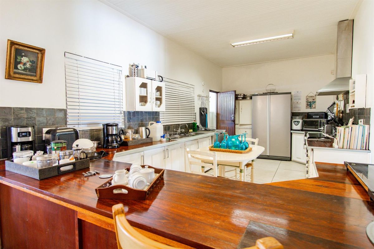 A functional kitchen featuring wooden countertops, white cabinetry, tiled splashbacks, and a stainless steel extractor fan.