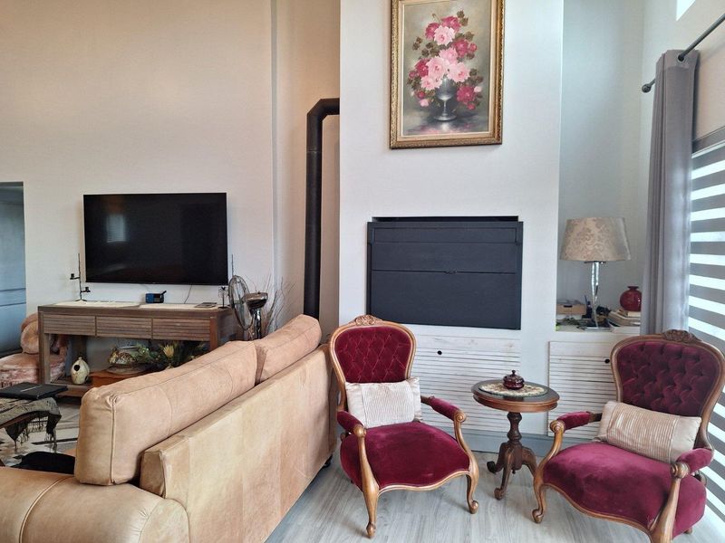 A spacious living room featuring a built-in fireplace with a flue, high ceilings, and light-toned flooring, creating a comfortable and inviting atmosphere.