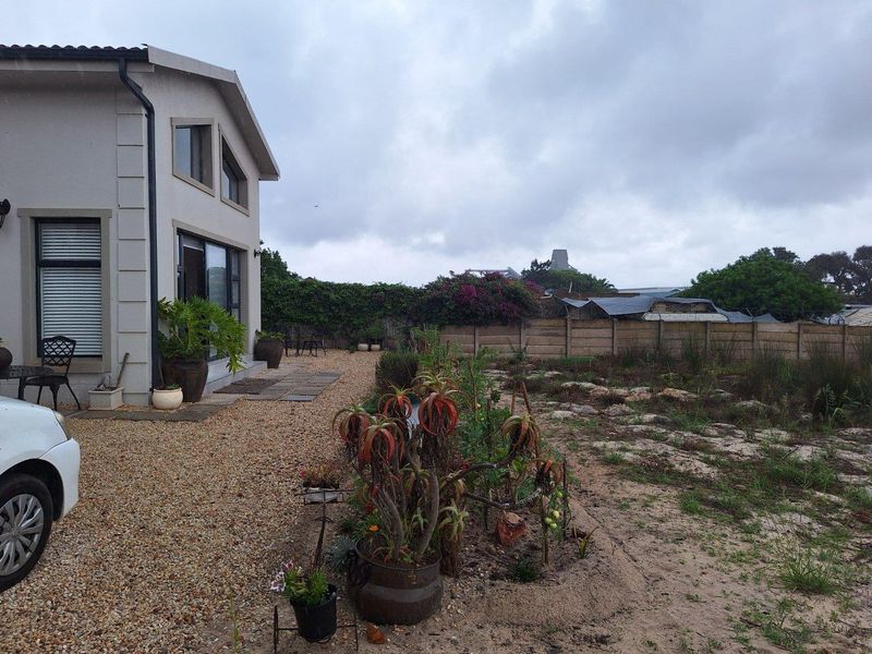A view of the rear exterior of the house featuring a gravel patio area and a large, undeveloped garden space with perimeter fencing.