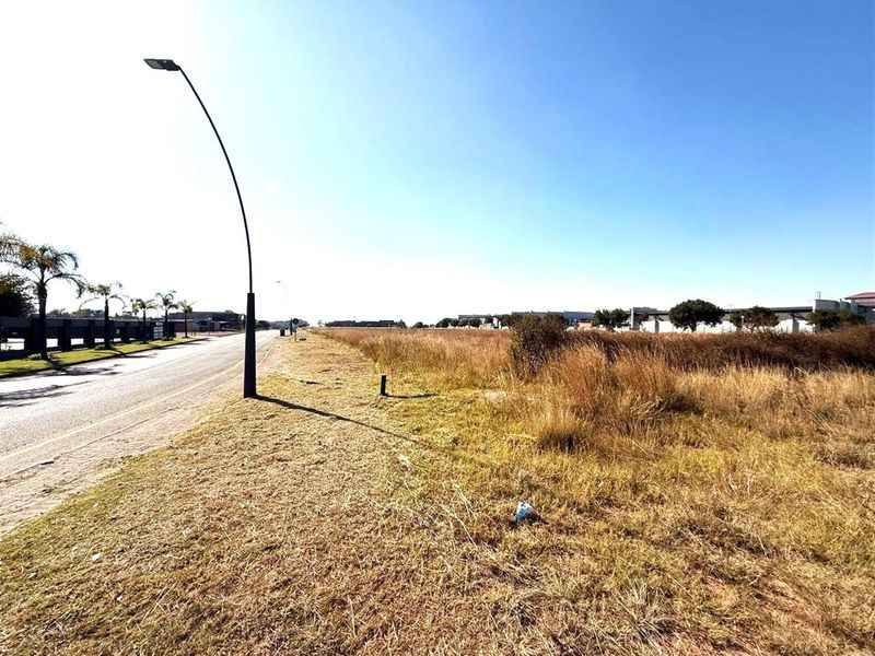 A view of the vacant commercial land adjacent to the paved road, featuring established street lighting and surrounding commercial infrastructure.