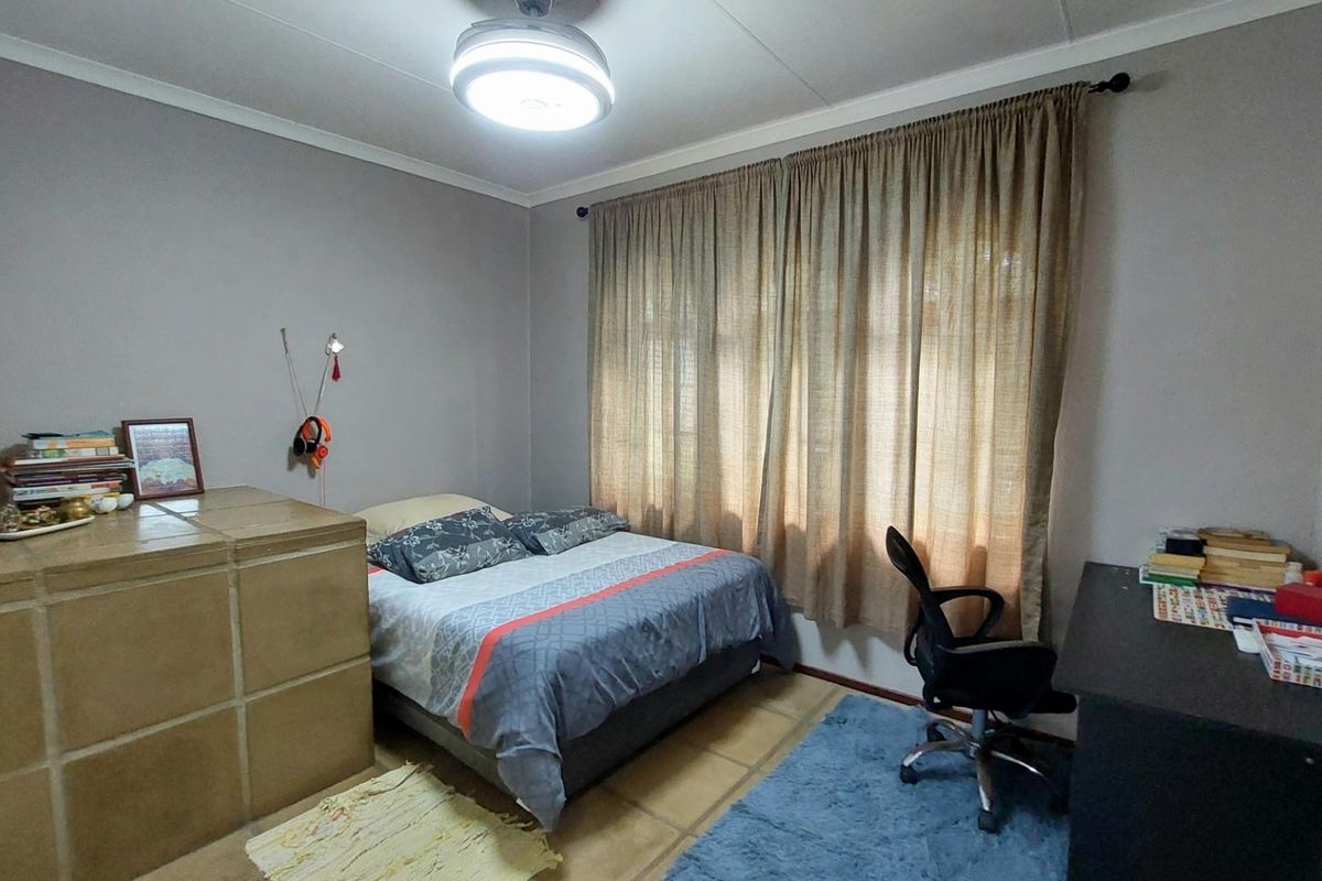 A functional bedroom featuring tiled flooring, neutral wall paint, and a central ceiling light fixture.