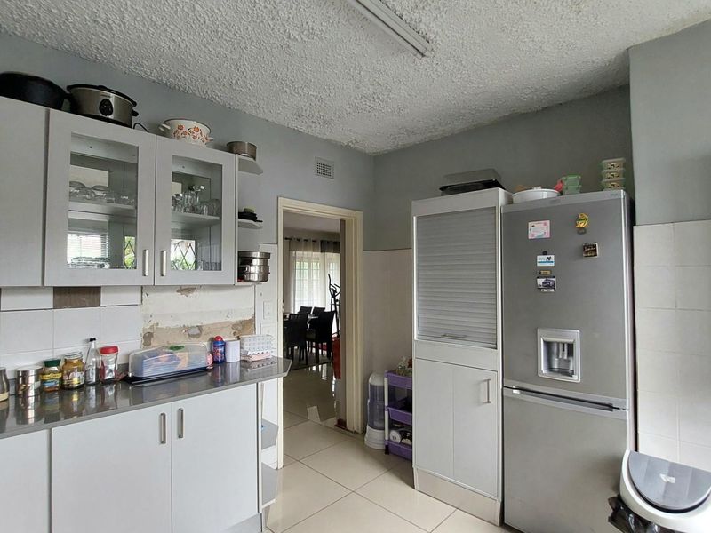 A functional kitchen featuring grey cabinetry, stainless steel countertops, and tiled flooring, requiring some cosmetic updates to the wall finishes.