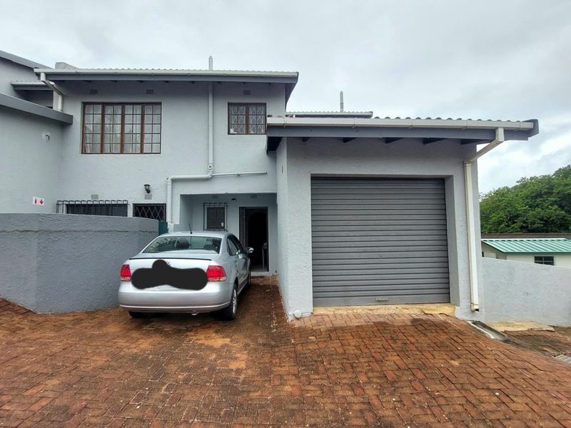 Front elevation of the apartment featuring a paved driveway, single garage with roller door, and main entrance access.