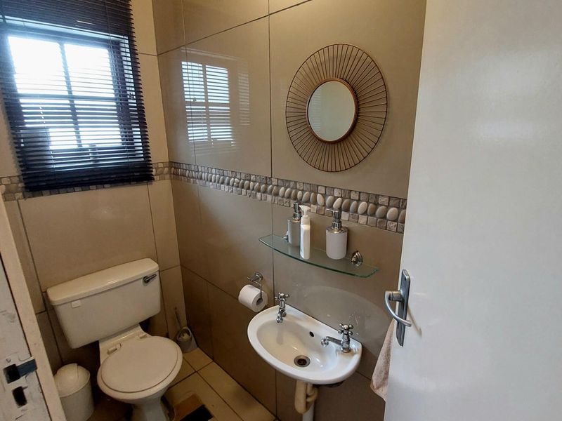 Compact guest bathroom featuring floor-to-ceiling wall tiles, a wall-mounted basin, and a standard toilet.