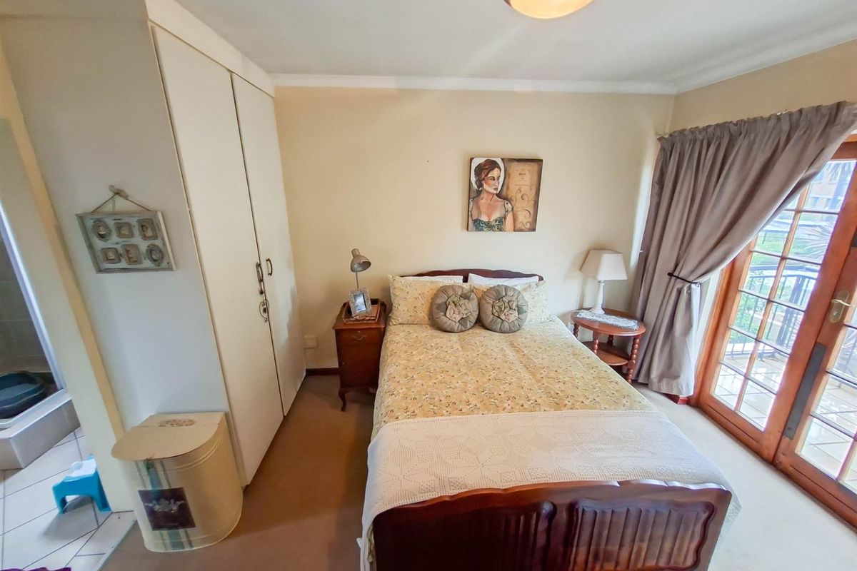 A bedroom featuring built-in cupboards, carpeted flooring, and a glass-paneled door providing access to an outdoor balcony area.