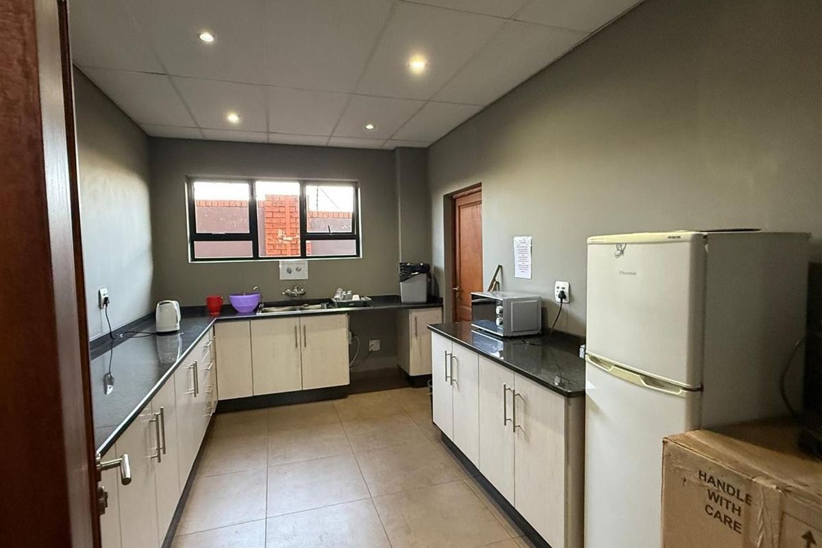 A functional commercial kitchen featuring granite countertops, light-toned cabinetry, tiled flooring, and recessed ceiling lighting.