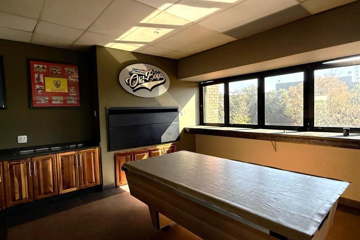A commercial entertainment or lounge area featuring built-in wooden cabinetry, a large window with natural light, and a drop ceiling.