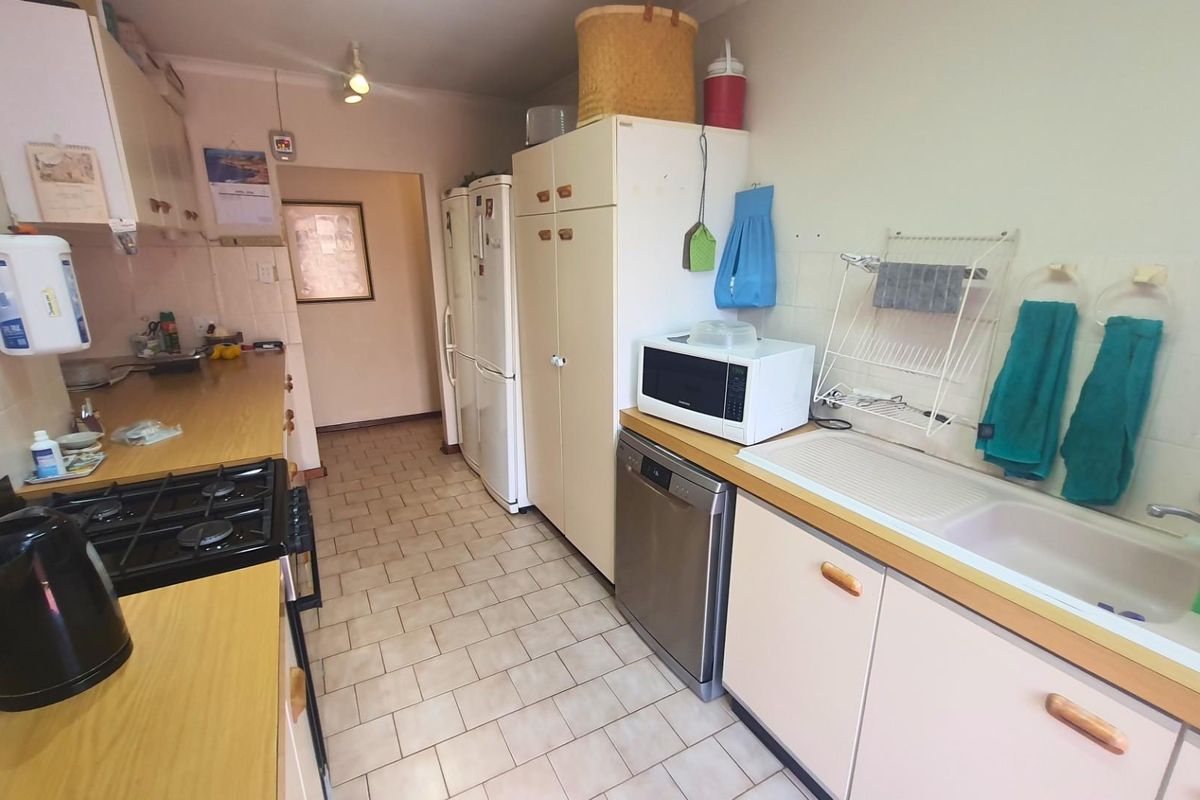 Functional kitchen featuring laminate countertops, gas hob, built-in cabinetry, and tiled flooring, offering a practical layout with ample storage space.