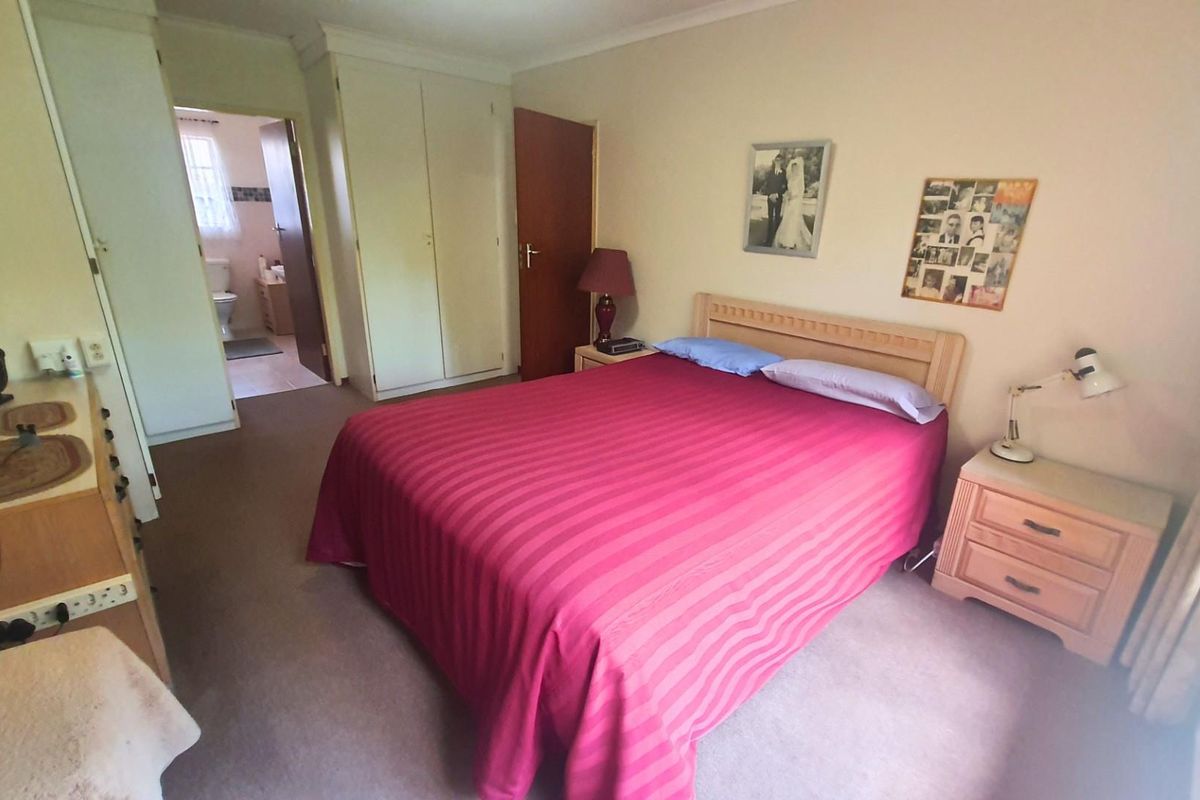 A carpeted bedroom featuring built-in cupboards and direct access to an en-suite bathroom.