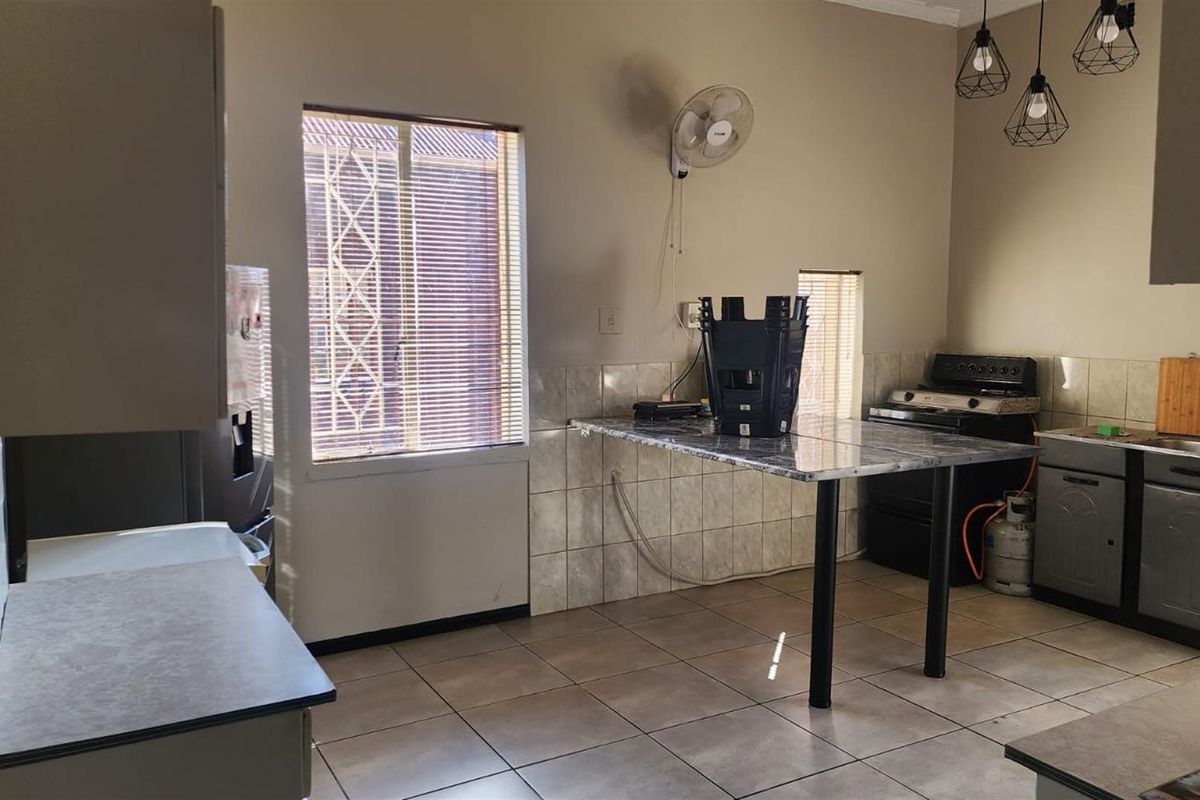 Functional kitchen featuring tiled flooring, built-in cabinetry, a breakfast bar, and a window with security bars.