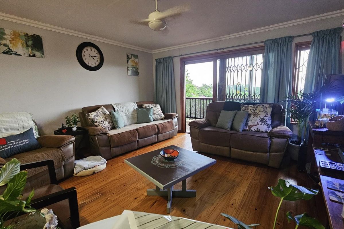 A comfortable living room featuring warm hardwood flooring, a ceiling fan, and a sliding glass door providing access to an outdoor balcony.