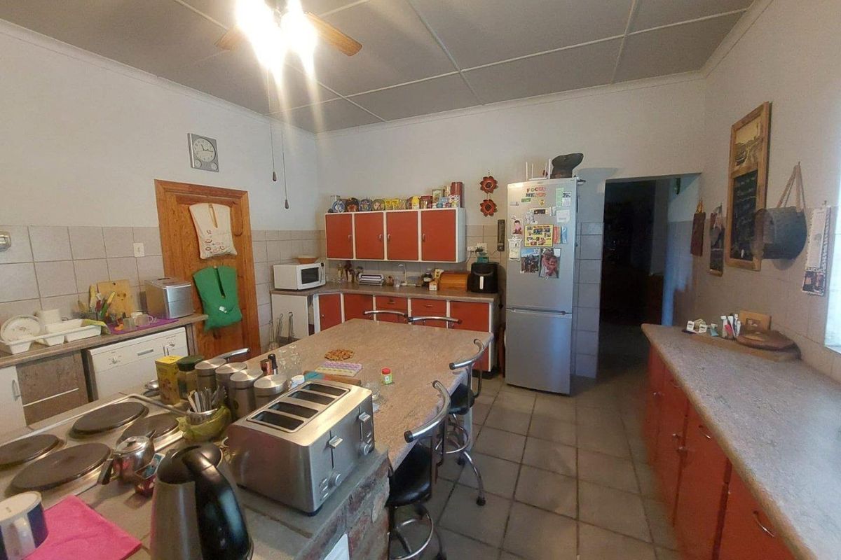A functional kitchen featuring a central island with a built-in hob, ample cabinetry, and tiled flooring, offering a practical layout for daily meal preparation.