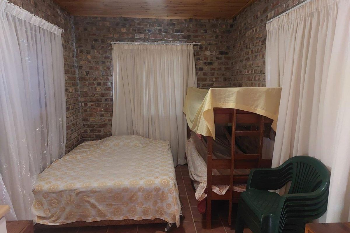 A rustic bedroom featuring exposed brick walls, tiled flooring, and a timber-paneled ceiling, providing a cozy and traditional farm-style aesthetic.
