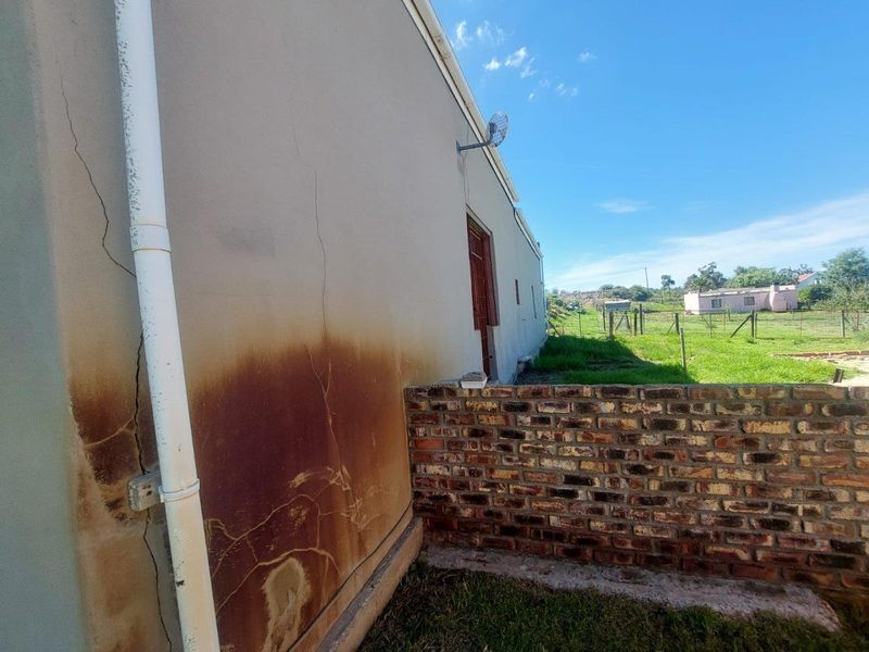 Exterior view of the property showing significant vertical wall cracking and extensive staining on the side facade.