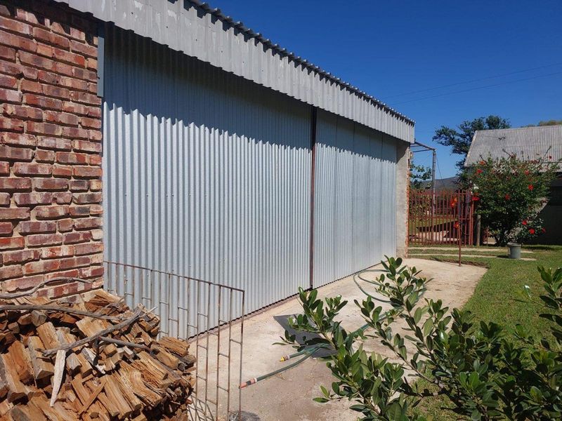 Exterior view of a farm outbuilding featuring corrugated metal cladding and brick masonry construction.