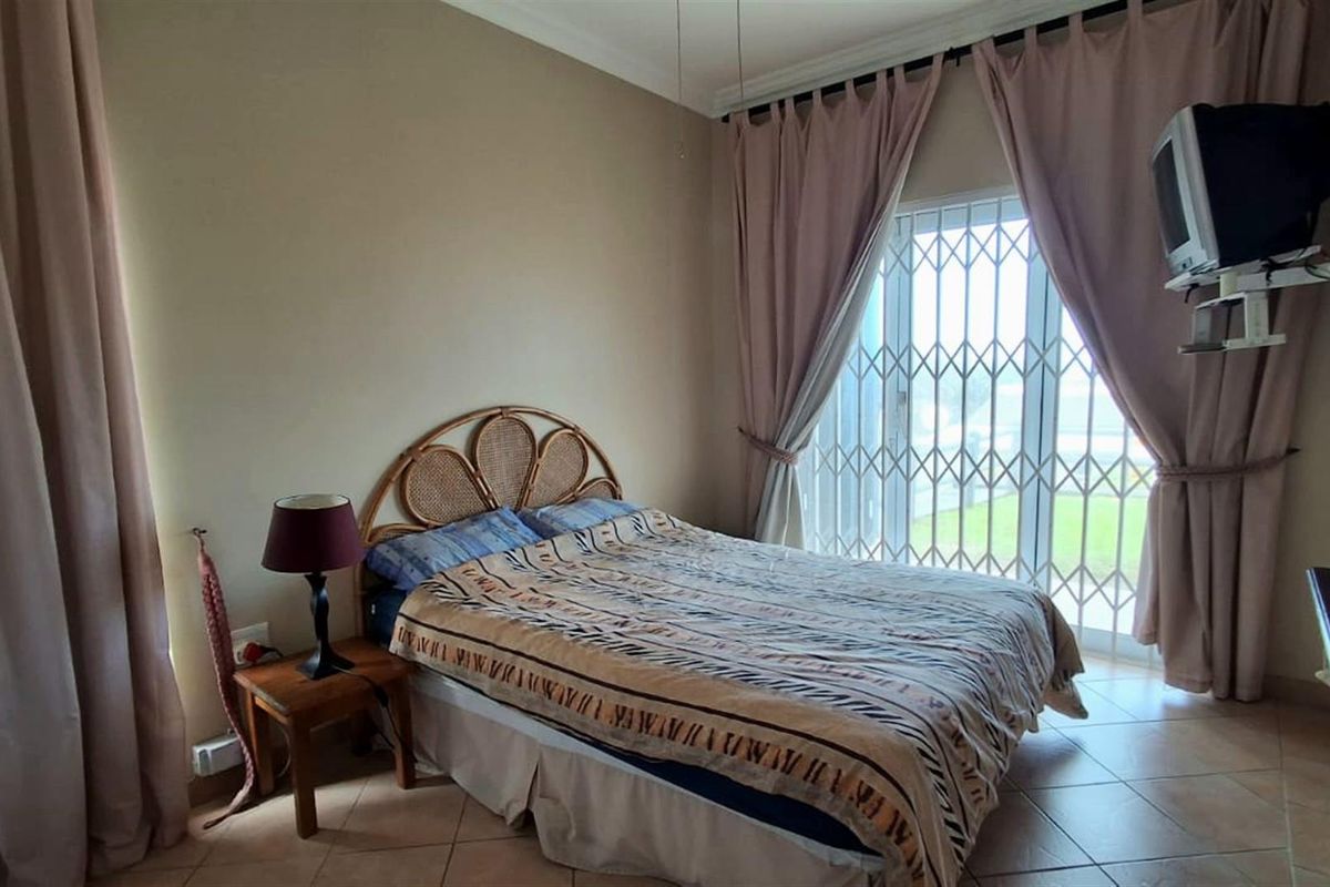 A bedroom featuring tiled flooring and a sliding glass door with a security gate, providing access to the exterior.