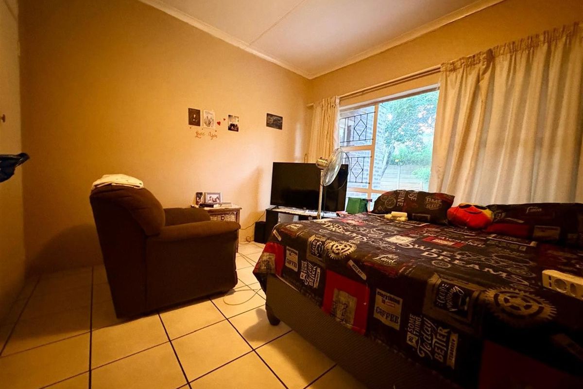 A bedroom featuring tiled flooring and a security gate on the window, providing a functional space with standard finishes.