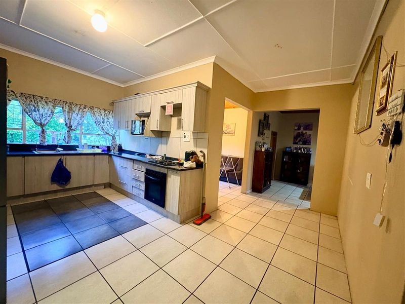 Functional kitchen featuring built-in cabinetry, integrated oven, hob, and tiled flooring, offering a practical layout with direct access to adjacent living areas.