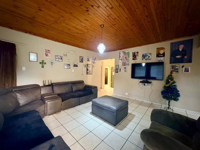 A living room featuring ceramic floor tiles and a timber tongue and groove ceiling, providing a functional and lived-in space.