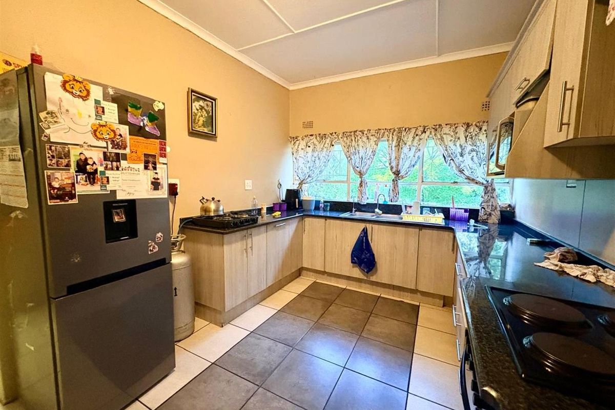 Functional kitchen featuring laminate cabinetry, granite countertops, and ceramic floor tiles, offering a practical layout with ample workspace and natural light.
