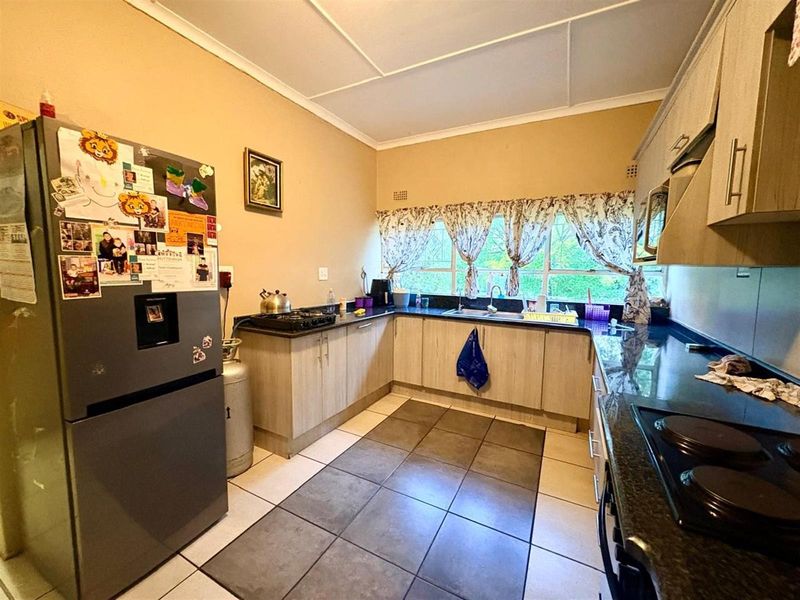 Functional kitchen featuring laminate cabinetry, granite countertops, and ceramic floor tiles, offering a practical layout with ample workspace and natural light.