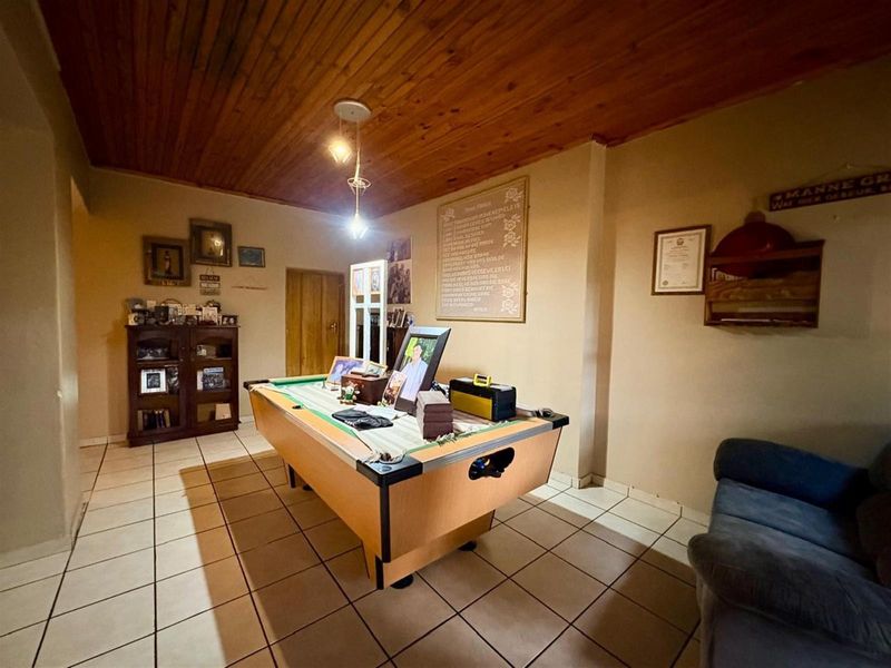 A living area featuring a timber tongue and groove ceiling and ceramic floor tiles, currently utilized as a recreational space.