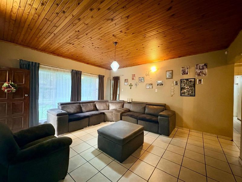 Spacious living room featuring a warm timber tongue and groove ceiling, neutral ceramic floor tiles, and large sliding glass doors for natural light.