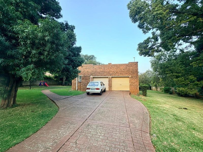 Front view of a brick-faced double garage with a paved driveway and surrounding established garden.