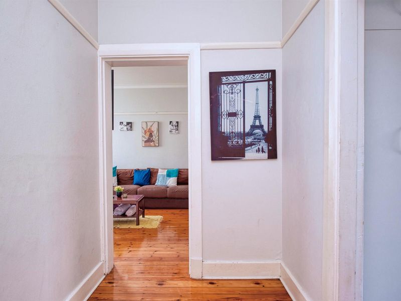 A bright hallway featuring polished timber flooring and a built-in cupboard, providing access to the adjacent living area.