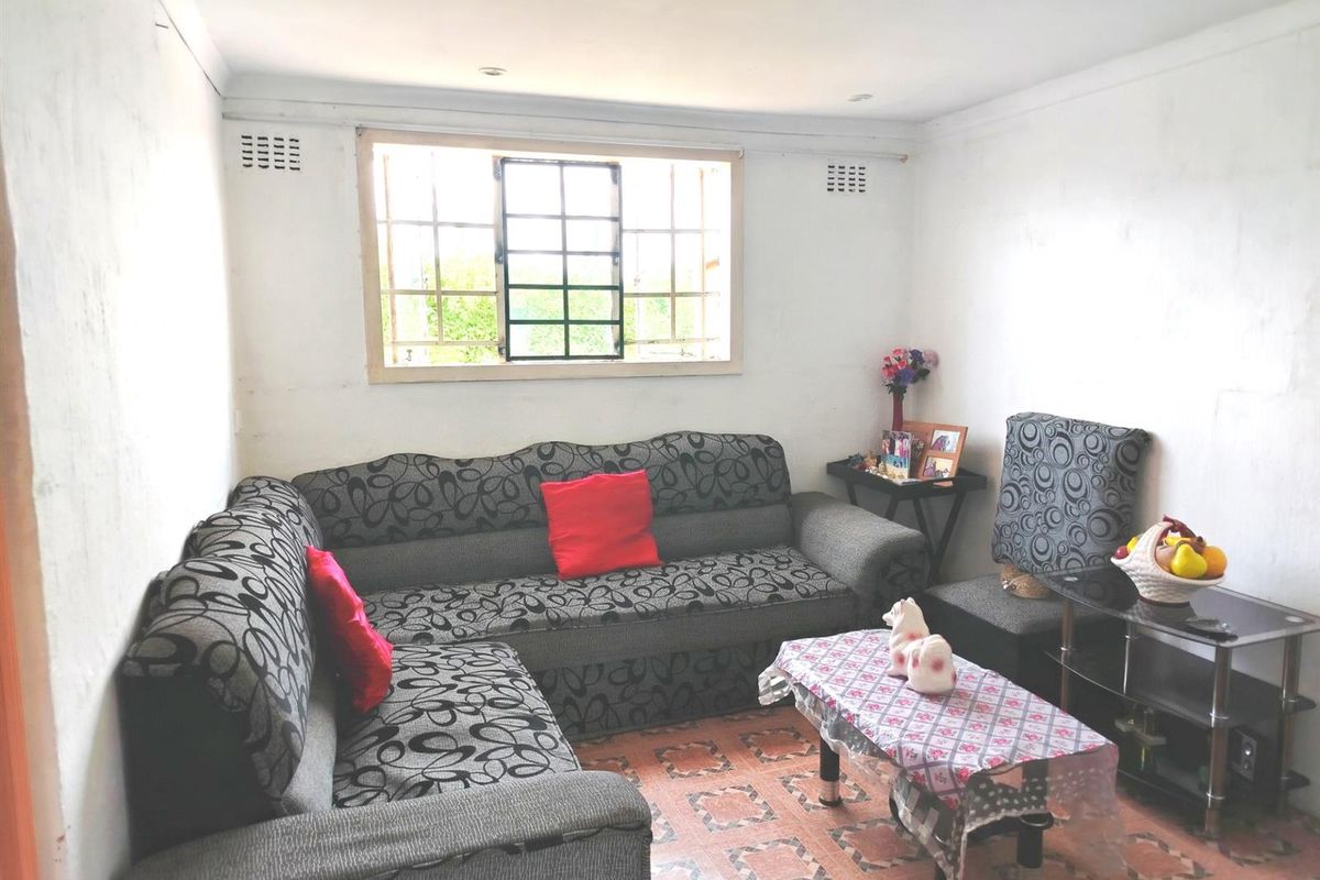 A living room featuring tiled flooring, recessed lighting, and a window fitted with security bars.