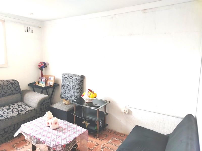 A living room area featuring tiled flooring and plain walls, requiring cosmetic updates to improve the overall aesthetic and condition of the space.