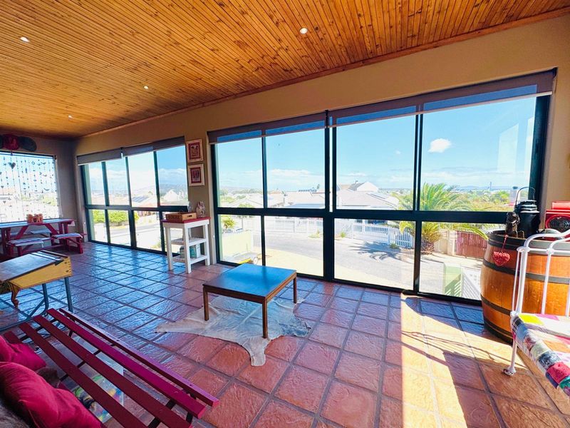 Enclosed patio area featuring terracotta floor tiles, a timber-clad ceiling with recessed lighting, and expansive windows offering neighbourhood views.