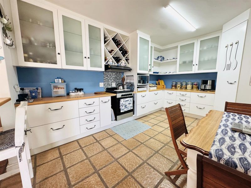 A functional kitchen featuring white cabinetry, a built-in wine rack, laminate countertops, and tiled flooring with a dedicated dining area.