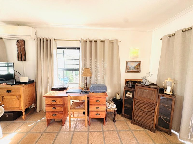 A living area featuring tiled flooring and a wall-mounted split-system air conditioner, providing a functional space with natural light.