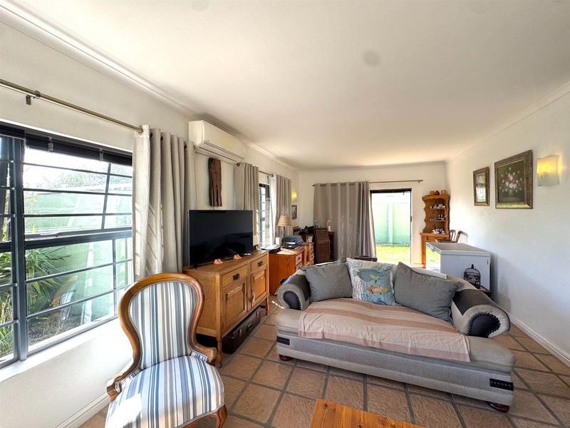 A living room featuring tiled flooring, split-system air conditioning, and access to the rear garden through a sliding glass door.
